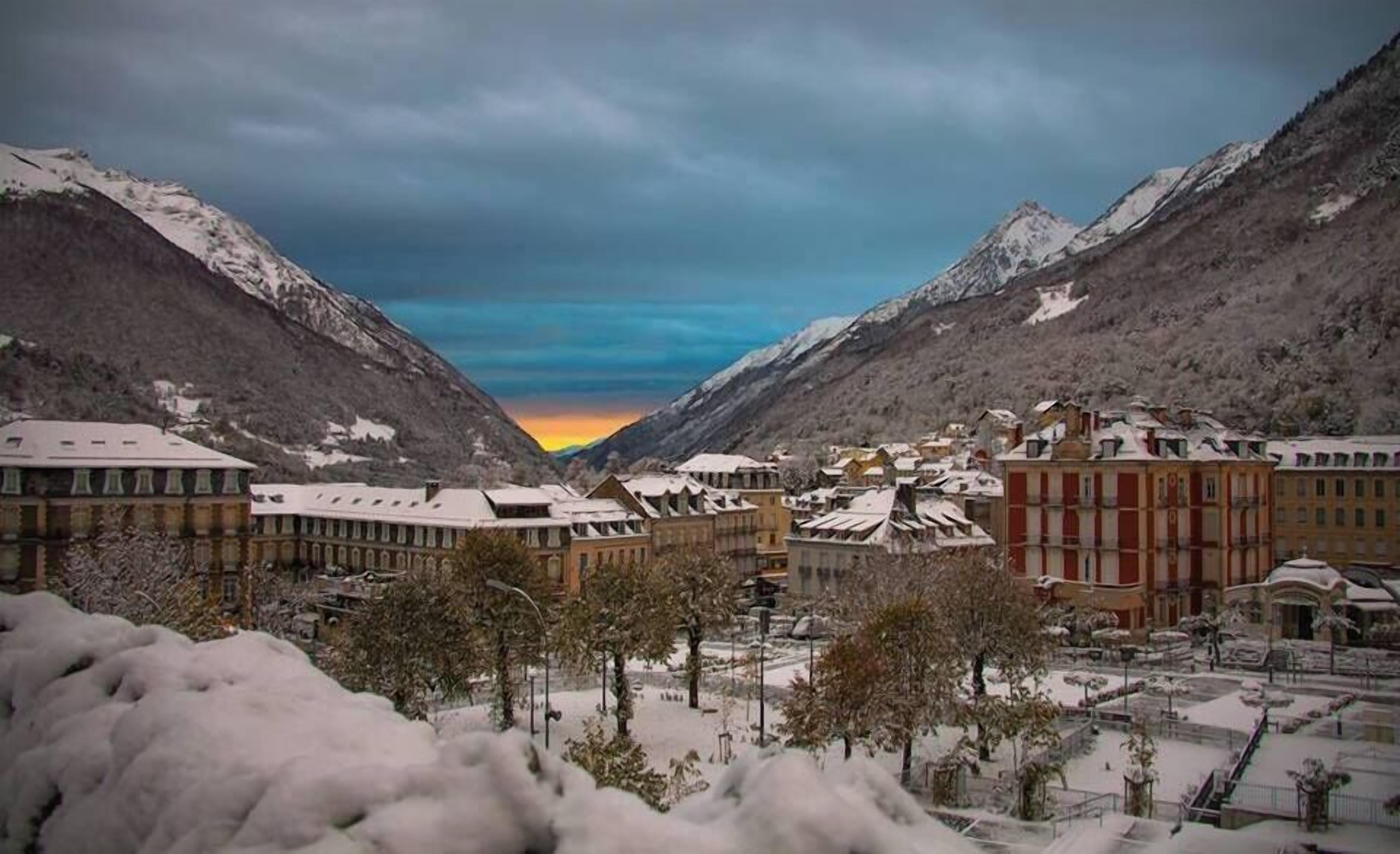 Une ville recouverte de neige, avec des bâtiments et des montagnes en arrière-plan.
