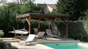 A backyard with a swimming pool, lounge chairs, and a pergola.
