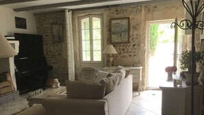 A living room with a sofa, a piano, and a stone wall.