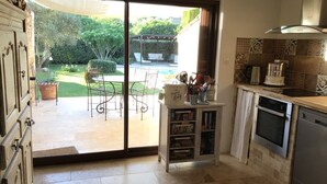A kitchen with a sliding glass door leading to a patio, a small cabinet with kitchen items, and a dishwasher.