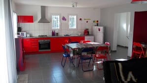 Una cucina moderna con mobili rossi, un piano cottura a gas e un'area pranzo con sedie blu e rosse.