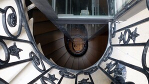 Eine Wendeltreppe mit aufwendigen schwarzen Metallgeländern und einer zentralen Holzhandrails.