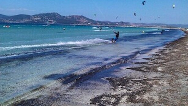 A beach with clear water and a person windsurfing. - Charming T1 completely renovated, with large terrace, in the heart of Giens. (Hyères)