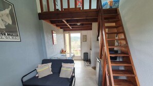 A room with a bed, a desk, and a wooden staircase. - Charming T1 completely renovated, with large terrace, in the heart of Giens. (Hyères)