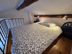 Una camera da letto con un letto, un comodino, una lampada e una trave in legno al soffitto.