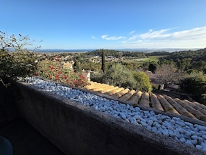 Una terrazza con un muro in pietra, ciottoli e vista su una città con case e vegetazione.