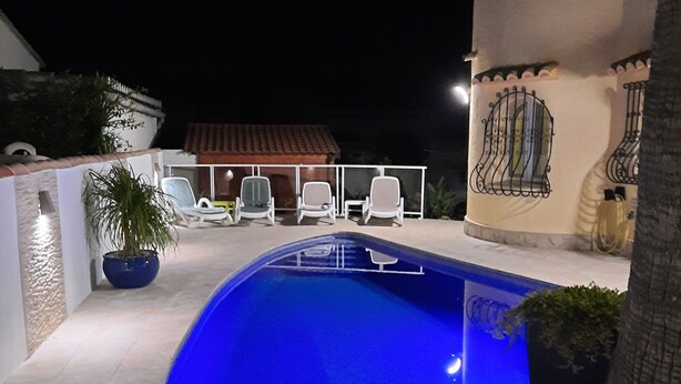 A swimming pool with white lounge chairs and a decorative wall. - CHARMING AIR-CONDITIONED VILLA WITH PRIVATE POOL, GARDEN, NEAR THE SEA AND SHOPS (ELS POBLETS)