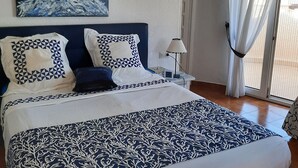 A bedroom with a large bed, a painting on the wall, and a window with curtains. - CHARMING AIR-CONDITIONED VILLA WITH PRIVATE POOL, GARDEN, NEAR THE SEA AND SHOPS (ELS POBLETS)
