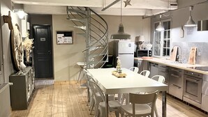A modern kitchen with a central island, stainless steel appliances, and a spiral staircase leading to an upper level.