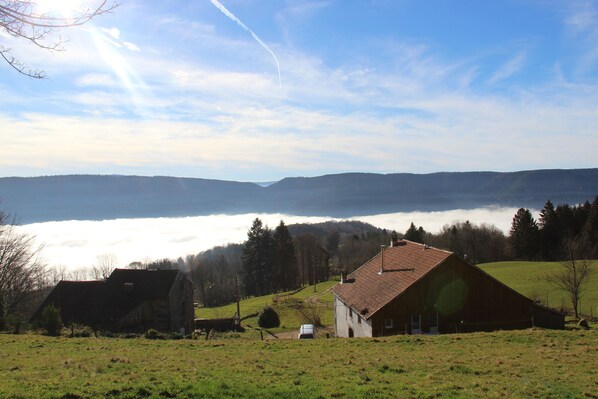 A rural landscape with a barn, open fields, and a distant view of a lake or valley. - CHARMING CHALET HAUTES VOSGES (Saulxures-sur-Moselotte)