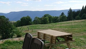 A picnic setup with two chairs and a table in a grassy field with a mountain view.