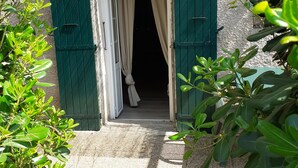 Una puerta con contraventanas verdes, que da a un interior oscuro.