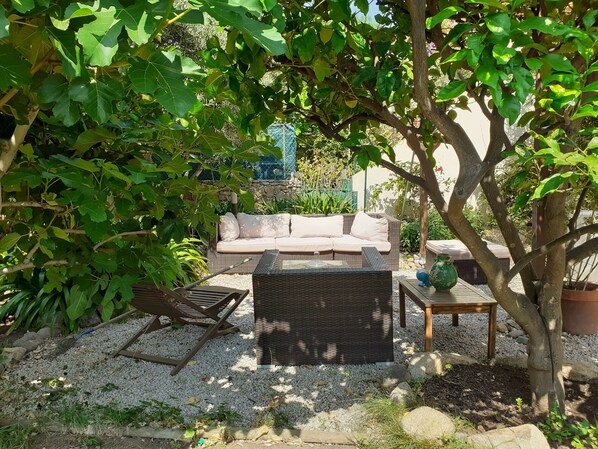 A patio area with a wicker sofa, two chairs, a small table, and a potted plant. - renovated apartment in bourgeois house (Calenzana)