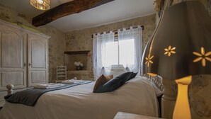 A bedroom with a large bed, a wooden headboard, a nightstand, a dresser, and a window with sheer curtains. - Rental in Nerac en Albret, stone built house, detached, renovated. (Nérac)