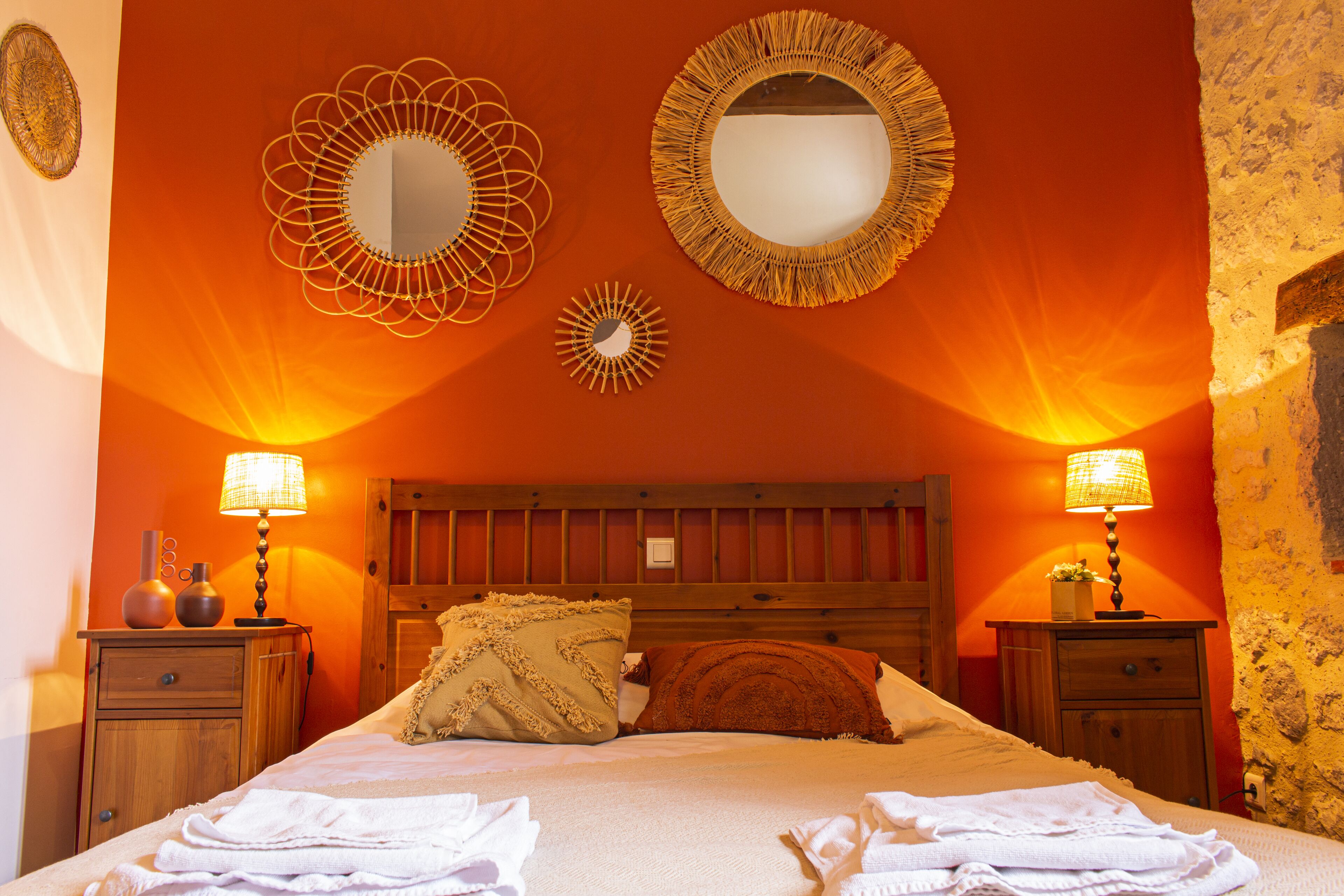 Une chambre d’hôtel avec un grand lit, deux tables de chevet avec des lampes et trois miroirs muraux.