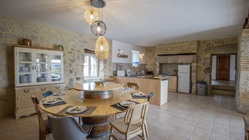 Una cocina amplia con una isla central, paredes de piedra y un comedor con sillas y una mesa.