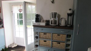 A kitchen with a coffee maker, a kettle, and a toaster on the counter. There are wicker baskets on the shelves below.