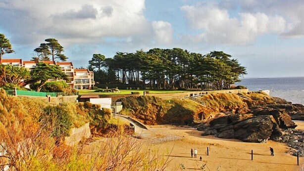 A coastal area with a sandy beach, rocky outcrops, and a row of buildings with a view of the sea. - House with garden by the sea in Pornic. Nearby beach. (Pornic)