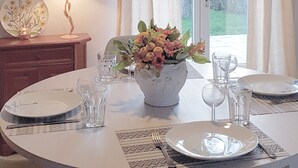 A dining table set with plates, glasses, and a vase of flowers. - House with garden by the sea in Pornic. Nearby beach. (Pornic)
