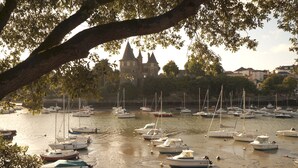 A marina with multiple boats docked, a historic building with towers in the background, and a large tree in the foreground. - House with garden by the sea in Pornic. Nearby beach. (Pornic)