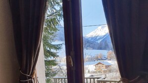 A room with a large window, a fur-covered bed, and a view of a snowy landscape with mountains and a lake. - Chalet Jamoo, an authentic renovated farmhouse in the heart of the Aravis mountains  (Entremont)