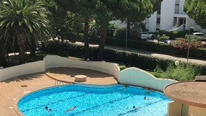 A swimming pool with multiple lanes, surrounded by a curved deck and palm trees. - Apartment with swimming pool - garage - air conditioning. - beach 200m away - WIFI (La Grande-Motte)