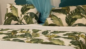 A bed with a tropical leaf pattern bedspread and matching pillows.