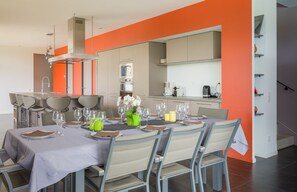 Un espace repas moderne avec une grande table dressée pour six personnes, entourée de chaises.