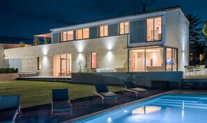 Une maison moderne à deux étages, dotée d’une piscine, d’un espace extérieur aménagé et d’un intérieur bien éclairé.