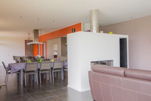 Una sala moderna con comedor, un sofá y una chimenea.