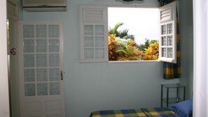 A bedroom with a window, a door, and a bed.