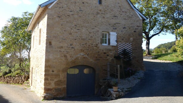 Un bâtiment en pierre avec une porte sombre, une petite fenêtre et une antenne parabolique.