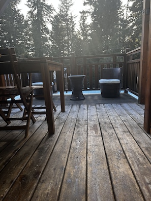 A wooden deck with a table and chairs, a wicker chair, and a bench. - Charming individual chalet, very comfortable, located at the bottom of the ski slopes (Chamrousse)
