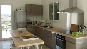 Een moderne keuken met roestvrijstalen apparatuur, een houten tafel en uitzicht door het raam.
