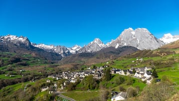A village nestled in a valley with a backdrop of snow-capped mountains.