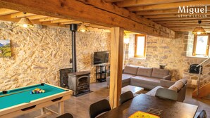 Un salon chaleureux avec une table de billard, un ensemble de canapés et un mur en pierre.