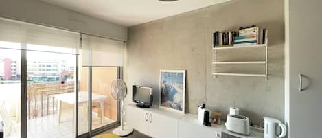 A modern kitchen with a large window, a dining area, and a kitchenette.