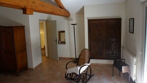A spacious room with a wooden ceiling, a rocking chair, a large wooden door, and a radiator. - Gîte in an early 18th-century Provencal farmhouse (Roquemaure)