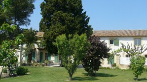 A white building with a tiled roof, surrounded by a well-maintained lawn and various trees. - Gîte in an early 18th-century Provencal farmhouse (Roquemaure)