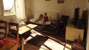 A living room with a sofa, two children, a wooden table, a TV, and a lamp.