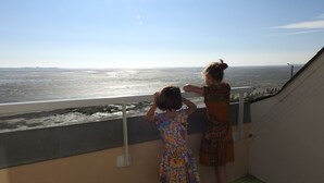 Two children looking out over a beach from a balcony.