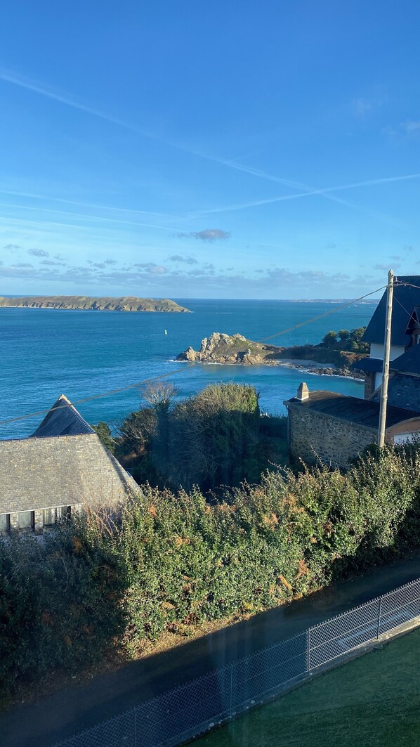 A coastal view with a stone building, a clear sky, and the sea.