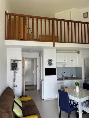 Un appartement moderne avec une chambre en mezzanine, un coin repas et une cuisine.