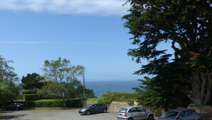 A parking lot with several cars, a stone wall, and a view of the sea. - PROMO - Duplex PANORAMIC SEA VIEW, Quiet and close to the BEACH  (Perros-Guirec)