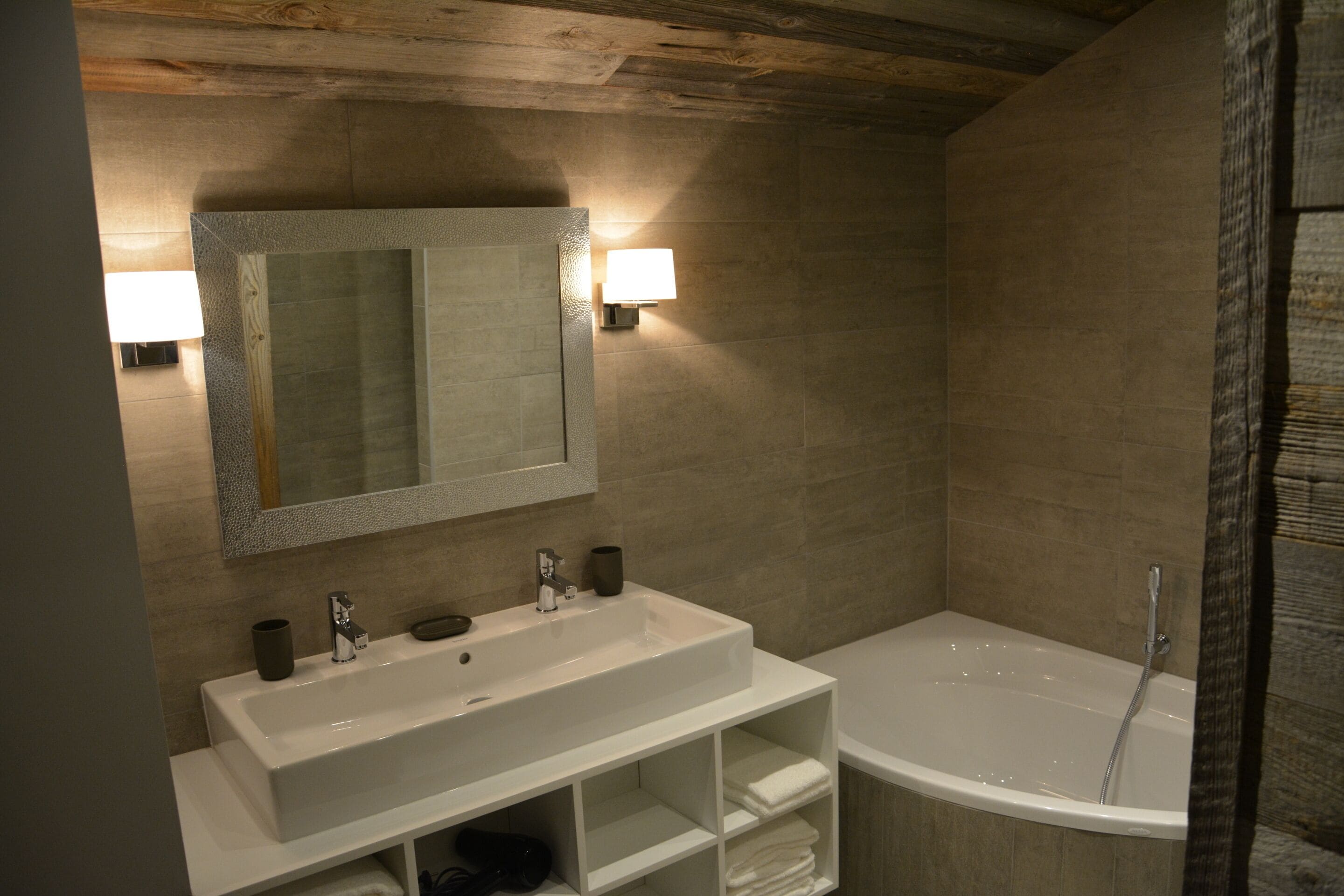 Un baño moderno con un espejo grande, dos lavamanos, una bañera y un perchero para toallas.