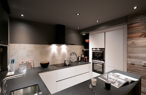 A modern kitchen with a central island, built-in oven, and stainless steel appliances. - Chalet Angora Collection Cassiopée (Font-Romeu-Odeillo-Via)
