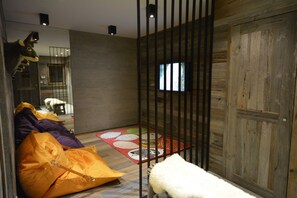 Una habitación con piso de madera, un espejo grande, un sofá, un tapete y un objeto blanco y mullido.