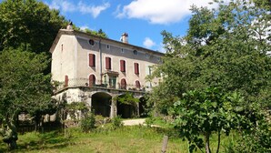 A historic building with a balcony, arched windows, and a stone bridge. - Large family house sleeps 16 in the heart of a beautiful medieval village (Génolhac)