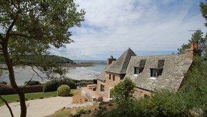 Ein Steinhaus mit geneigtem Dach mit Blick auf einen Strand.