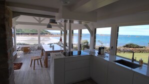 Eine moderne Küche mit großen Fenstern und Blick auf einen Strand.